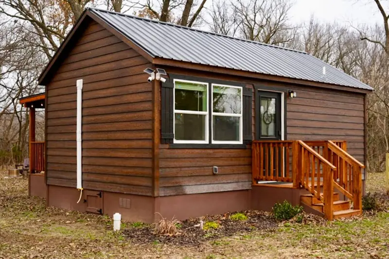 14x24 Tiny Home &ndash; Model 8701, exterior set among trees
