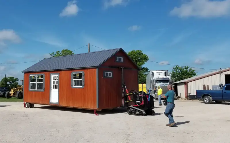 The crew moving a finished cabin across the lot with a remote-control mover