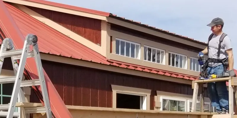 A crew member on scaffolding finishing a cabin roof