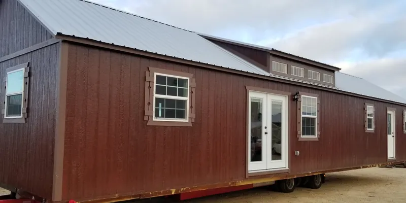 A finished cabin with French doors on a delivery trailer